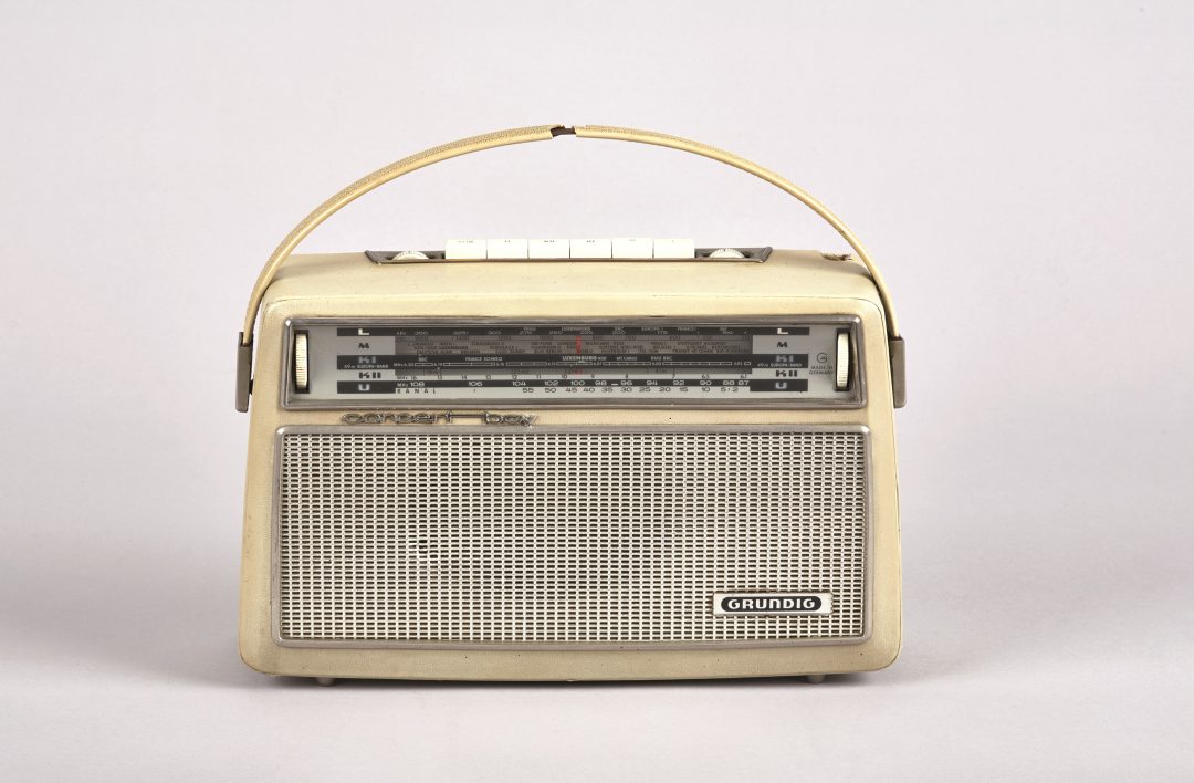 In 1965, a radio was an expensive household item, costing around 200 Deutsche Marks. Ceferina García García was therefore very proud when she told her employer at the tailor’s shop that her family now owned their own radio and could finally listen to Spanish-language news. She was especially pleased that they had successfully negotiated the price down. 
The daily Spanish-language broadcasts of the Westdeutscher Rundfunk (WDR) were of great importance to the family. They enabled them to stay informed about both life in Germany and events in Spain. In addition, the radio made it possible to receive broadcasts directly from Spain. 
Their daughter, Cristina Fernández García-Moser, remembers the radio from her childhood. For the children, however, its use was subject to strict rules: when their parents were listening to the Spanish-language programs, they had to remain completely quiet, “silent as death”. 
Today, the radio is on display in the permanent exhibition of the Ruhr Museum in Essen. © Ruhr Museum, Foto: Rainer Rothenberg